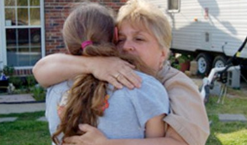 A woman hugs a teenage girl